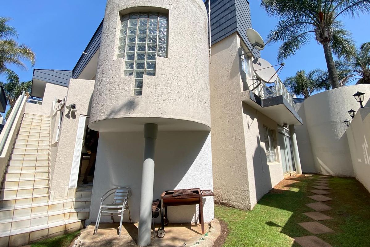 Rear exterior view of a cluster home featuring a distinctive cylindrical architectural element with glass block windows and an external staircase.