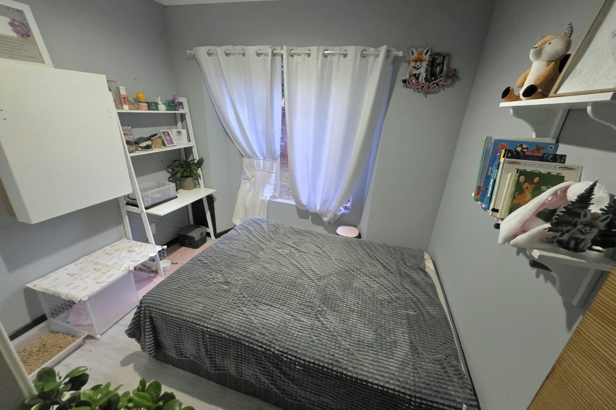 A functional bedroom featuring laminate flooring and a window with curtain rod, providing a neutral base for personalization.