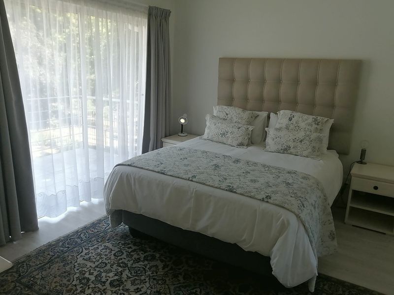 A well-lit bedroom featuring laminate flooring and a large sliding glass door providing access to an outdoor area.