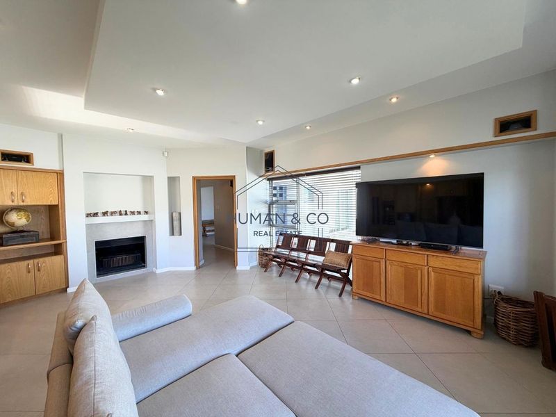 Spacious living room featuring tiled flooring, recessed ceiling lights, a built-in fireplace, and custom wooden cabinetry.