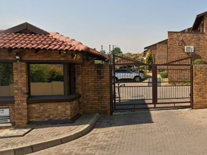 The entrance to the apartment complex features a brick guard house, secure gated access, and paved driveway, providing a secure entry point for residents.