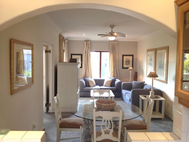 Open plan living and dining area featuring a central archway, ceiling fan, and neutral finishes, providing a functional and connected living space.