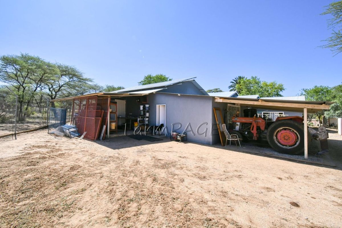 Exterior view of a small holding outbuilding featuring a covered carport area and adjacent utility space with metal roofing.