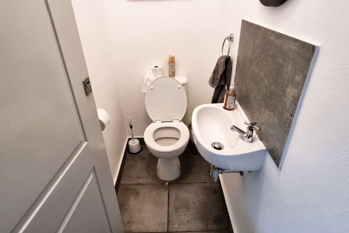 Compact guest bathroom featuring a wall-mounted basin with a stone-look splashback and a standard toilet.