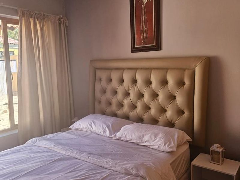 A bedroom featuring tiled flooring and crown molding, with natural light entering through the side window.