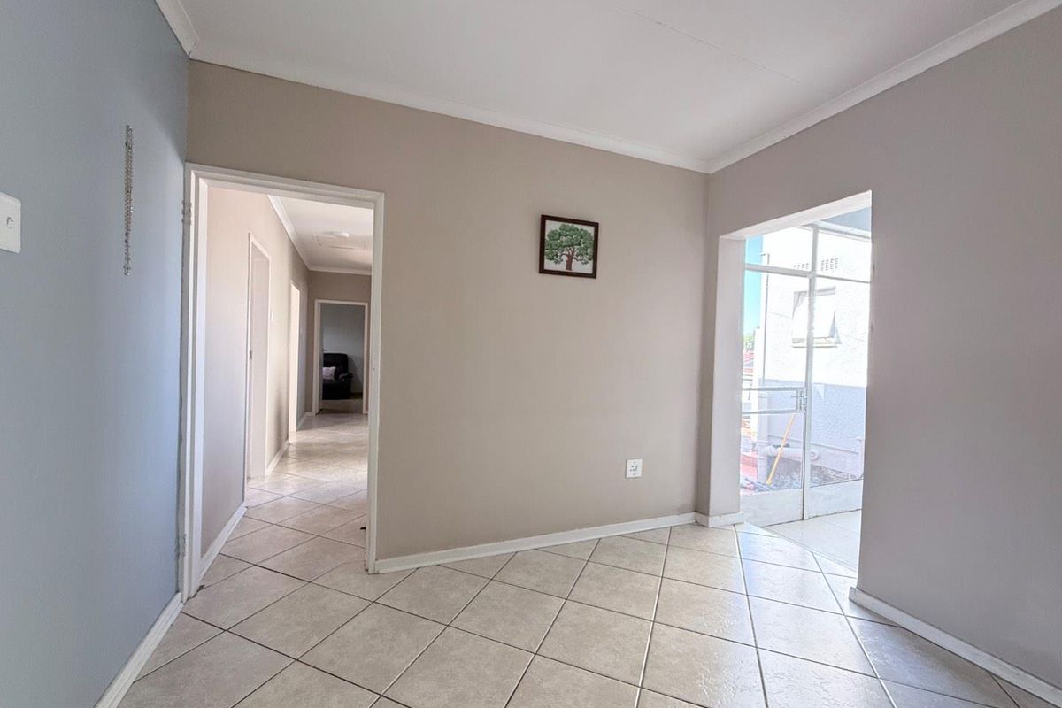 An empty living area featuring neutral wall tones, ceramic floor tiles, and direct access to an outdoor patio space.