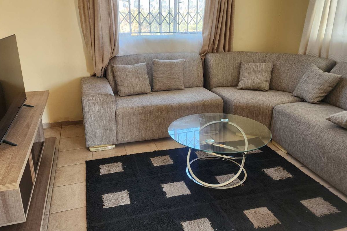 A functional living room featuring tiled flooring and a window with security bars, providing a comfortable and practical space for relaxation.