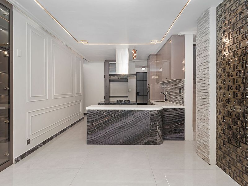 Modern, high-end kitchen featuring a striking marble island, sleek cabinetry, integrated appliances, and sophisticated decorative wall finishes with recessed lighting.