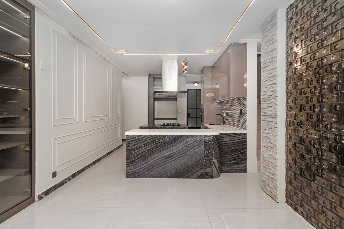 Modern, high-end kitchen featuring a striking marble island, sleek cabinetry, integrated appliances, and sophisticated decorative wall finishes with recessed lighting.