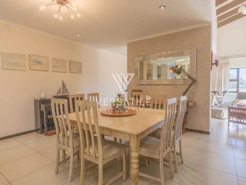 A bright dining area featuring neutral tiled flooring, recessed downlighting, and a large built-in wall mirror, creating an open and inviting atmosphere.