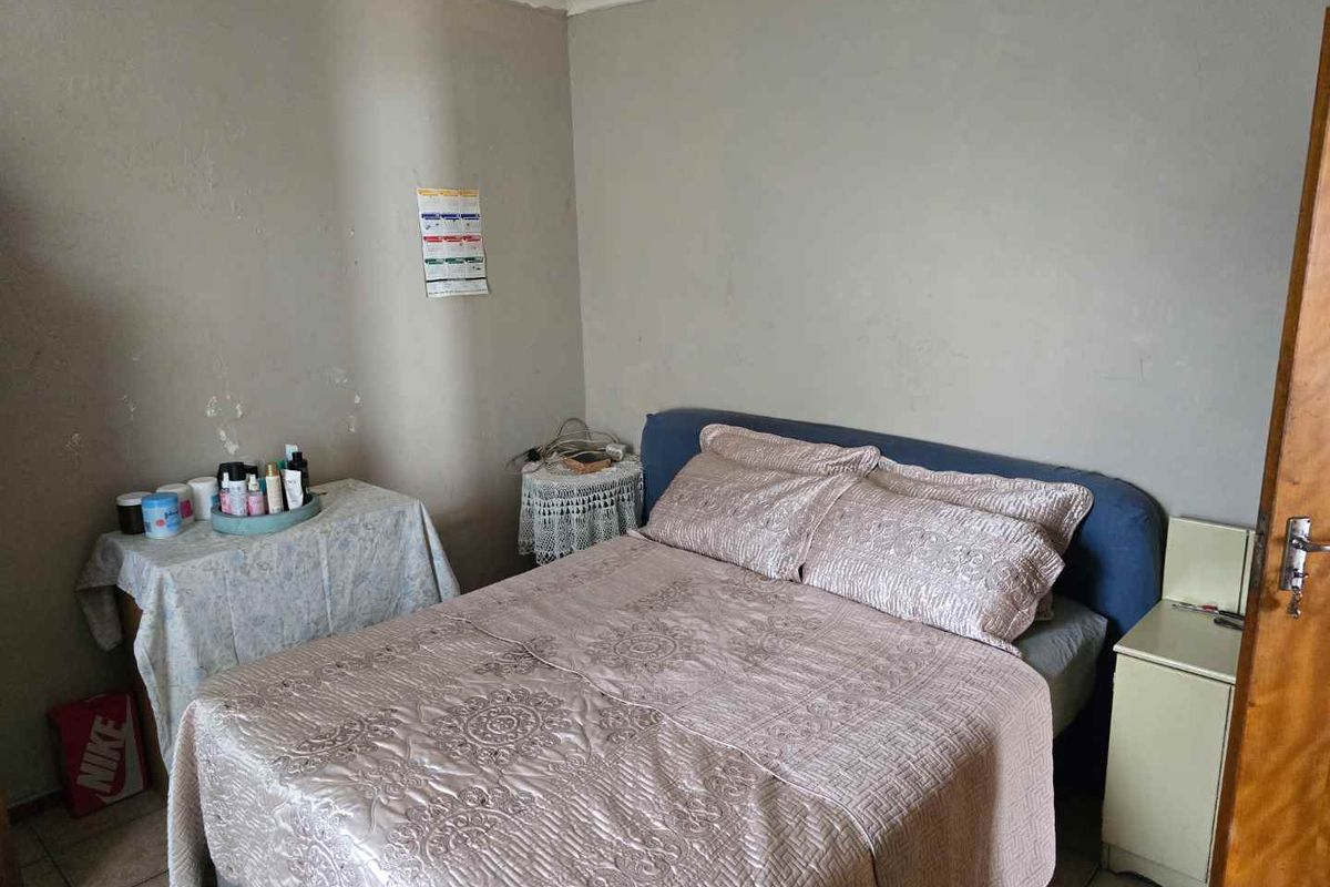 A bedroom featuring tiled flooring and neutral wall finishes, providing a functional space for rest.