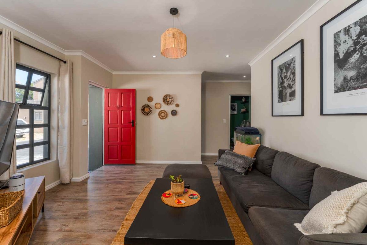 A bright living room featuring wood-look flooring, a bold red front door, and recessed lighting, creating a welcoming and functional living space.