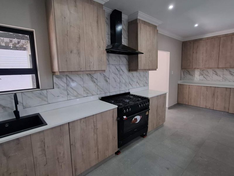 Modern kitchen featuring wood-look cabinetry, marble-effect backsplash, quartz countertops, and a black gas stove with matching extractor fan.
