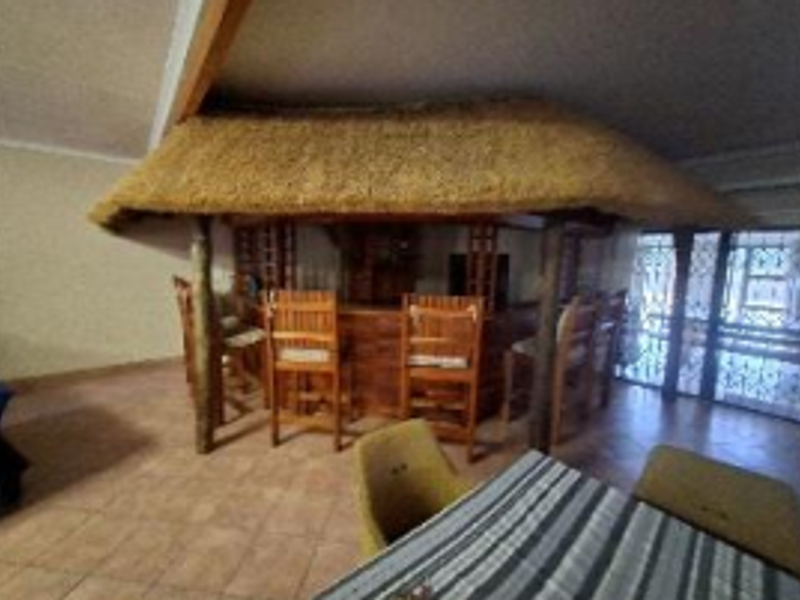 Indoor entertainment area featuring a built-in bar with a decorative thatch roof and tiled flooring.