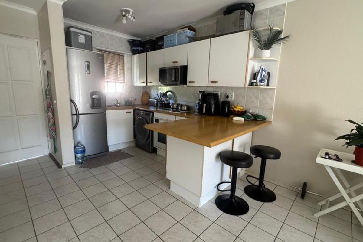 Compact kitchen featuring white cabinetry, tiled flooring, a built-in microwave, and a functional breakfast counter area.