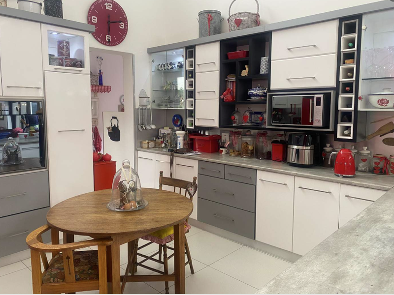 A functional kitchen featuring modern two-tone cabinetry, integrated appliances, glass display shelving, and a dedicated breakfast nook area with tiled flooring.