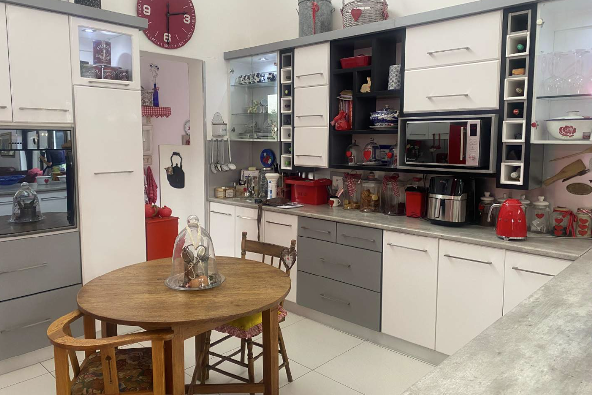 A functional kitchen featuring modern two-tone cabinetry, integrated appliances, glass display shelving, and a dedicated breakfast nook area with tiled flooring.