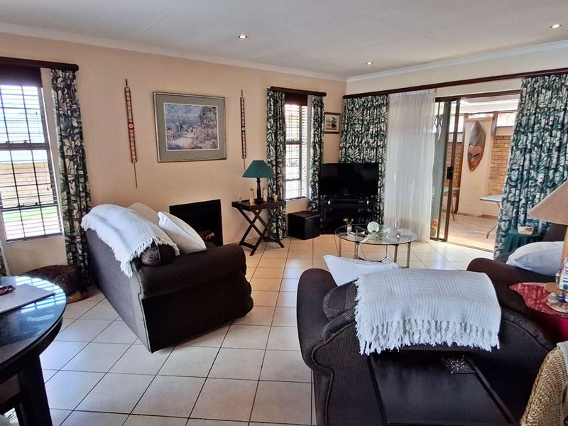 Spacious living room featuring tiled flooring, a built-in fireplace, and sliding glass doors that provide access to an outdoor patio area.