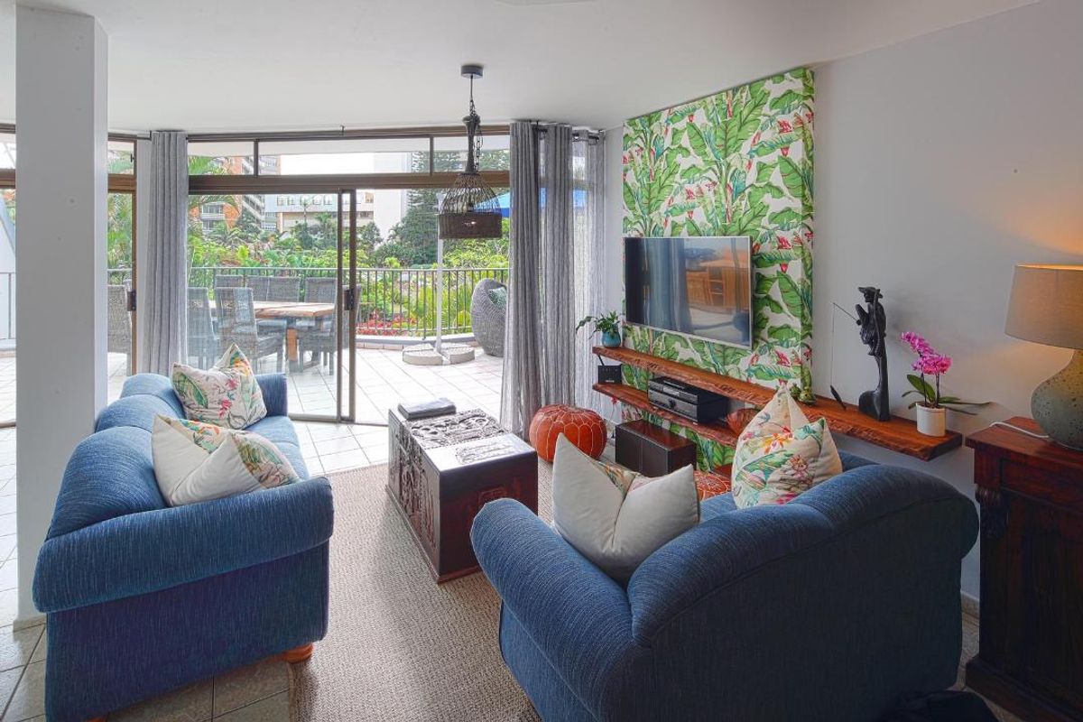 A bright living room featuring large sliding glass doors that open onto a spacious balcony, creating a seamless indoor-outdoor flow.