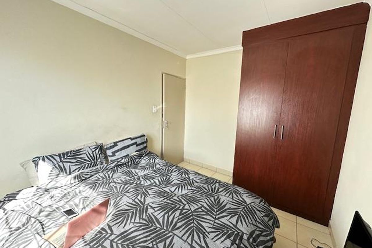 A functional bedroom featuring built-in wooden cabinetry and tiled flooring, offering a clean and simple living space.