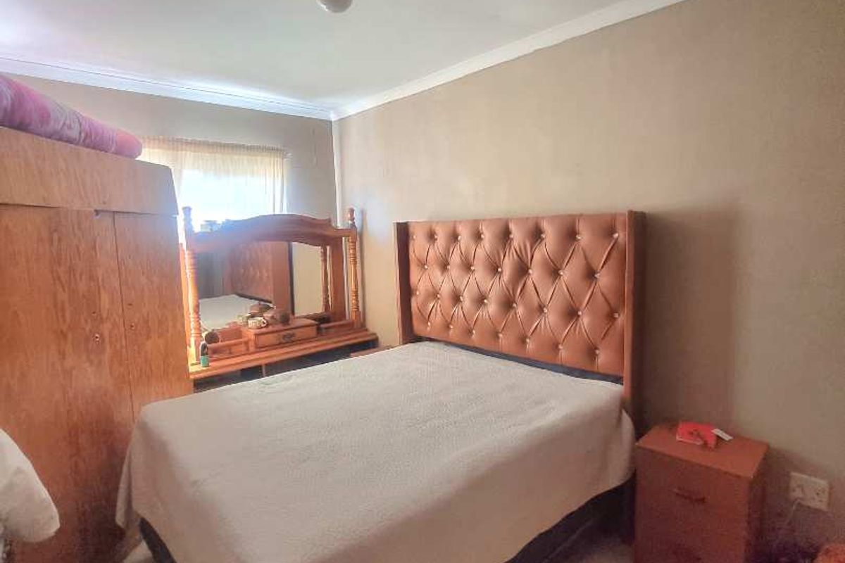 A bedroom featuring tiled flooring and neutral wall tones, providing a functional space for rest.