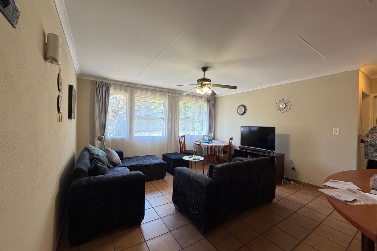 A functional living room featuring tiled flooring, a ceiling fan, and coved ceilings, providing a comfortable and well-lit space for relaxation.