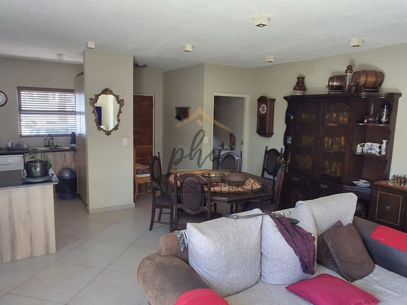 Open-plan living and dining area featuring a functional kitchen with island, tiled flooring, and recessed lighting, offering a versatile layout for modern living.