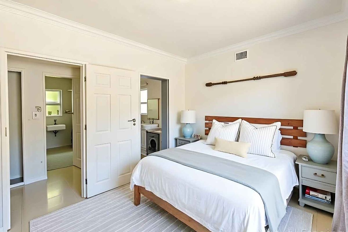 A well-maintained bedroom featuring crown molding, neutral flooring, and direct access to an en-suite bathroom.