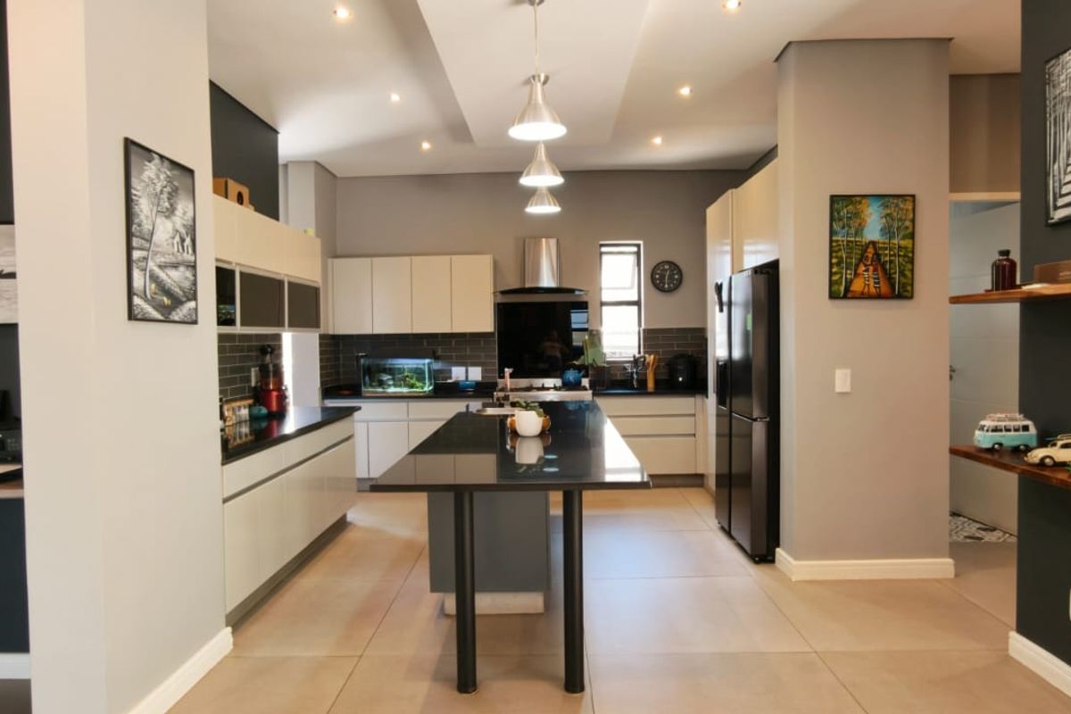 Modern kitchen featuring a central island, sleek cabinetry, stone countertops, and recessed lighting, creating a functional and contemporary culinary space.