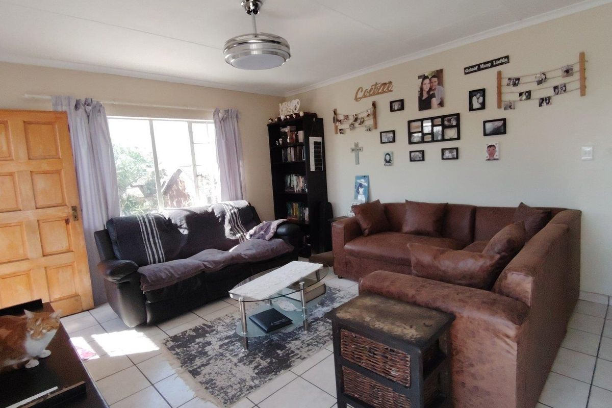 A functional living room featuring tiled flooring, a ceiling fan, and natural light from a large window.
