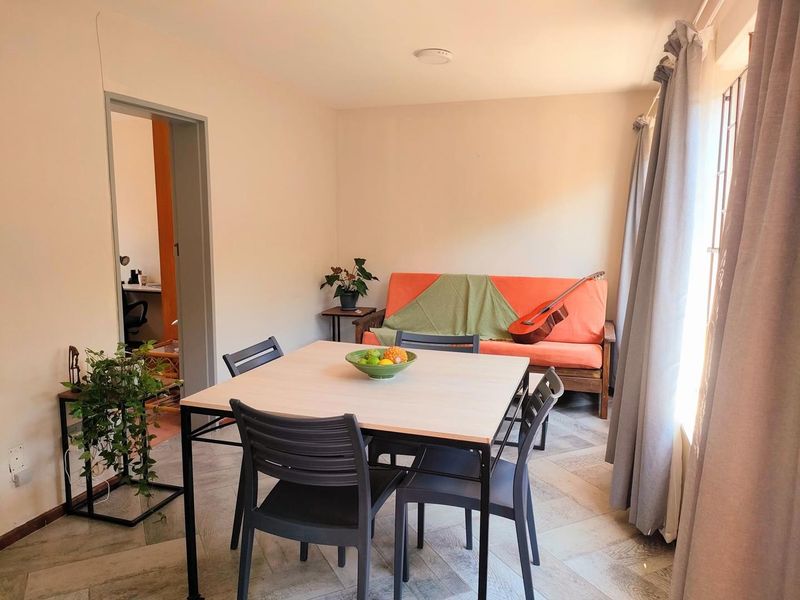 A functional living and dining area featuring tiled flooring and natural light, providing a versatile space for relaxation and meals.