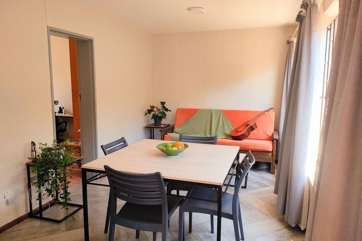 A functional living and dining area featuring tiled flooring and natural light, providing a versatile space for relaxation and meals.