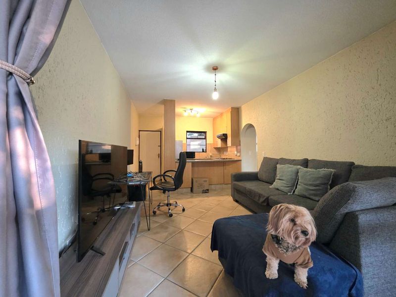 Open-plan living area featuring tiled flooring and a functional kitchen with built-in cabinetry and an extractor fan.