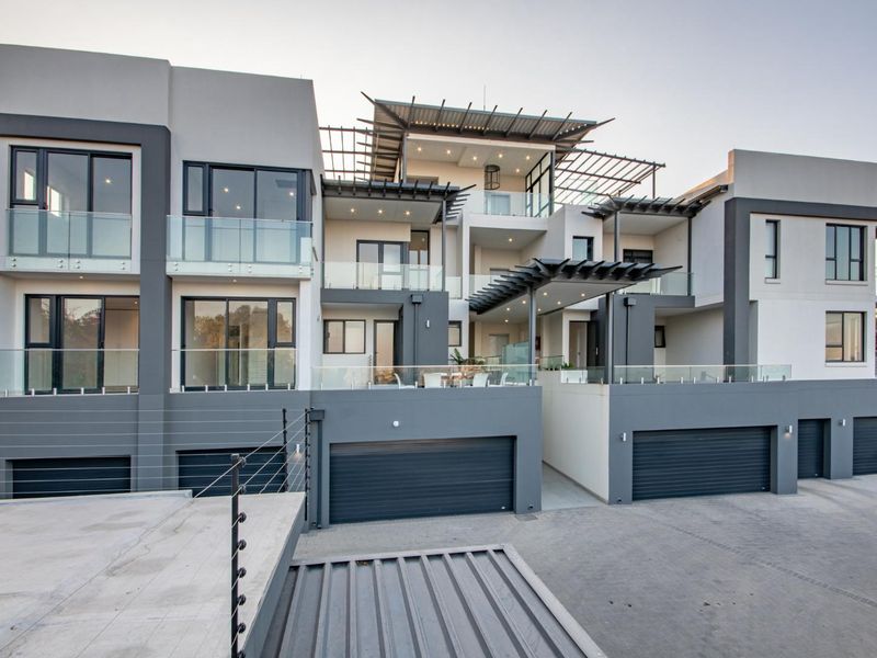 Modern multi-level penthouse exterior featuring contemporary architectural design, glass balustrades, integrated garage access, and stylish pergola structures.