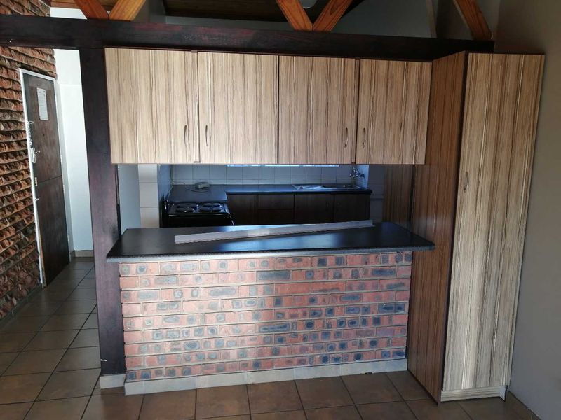 A functional kitchen featuring a brick breakfast bar, laminate cabinetry, built-in stove, and tiled flooring, offering a rustic aesthetic with potential for modern updates.