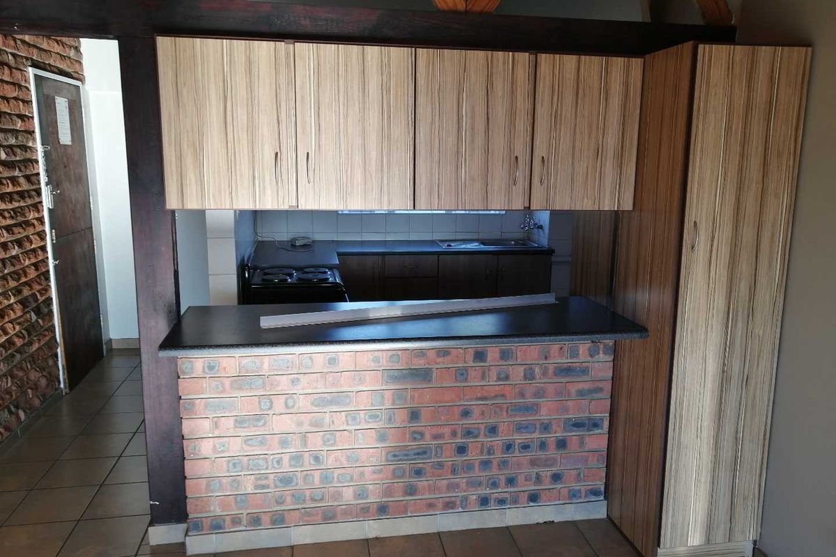 A functional kitchen featuring a brick breakfast bar, laminate cabinetry, built-in stove, and tiled flooring, offering a rustic aesthetic with potential for modern updates.