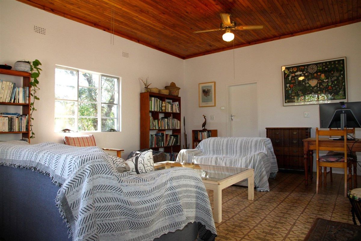 A living room featuring a warm timber-clad ceiling, a ceiling fan, and patterned tiled flooring, offering a comfortable and traditional living space.