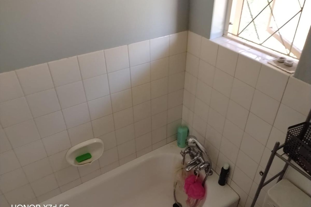 A functional bathroom featuring a standard bathtub with chrome fixtures and white ceramic wall tiling.