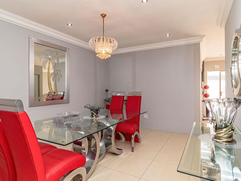 A well-maintained dining room featuring neutral tiled flooring, crown molding, and recessed downlighting, providing a clean and bright space for formal dining.