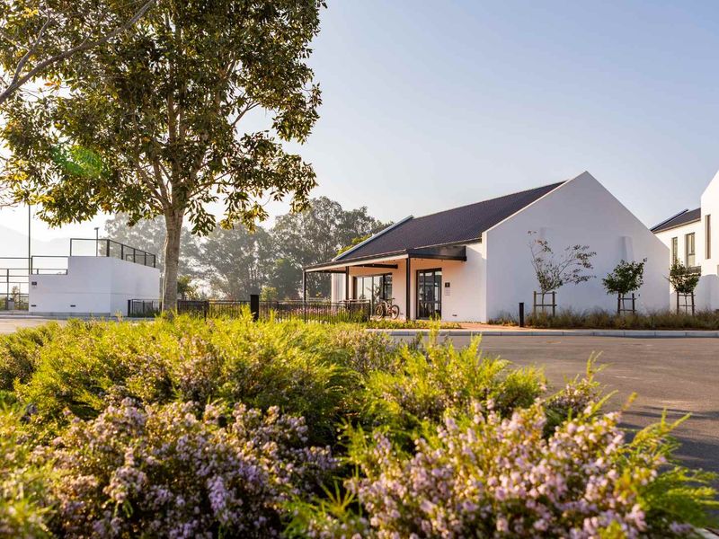 A well-maintained residential building exterior featuring a clean white facade, pitched roof, and landscaped surroundings with a paved driveway.