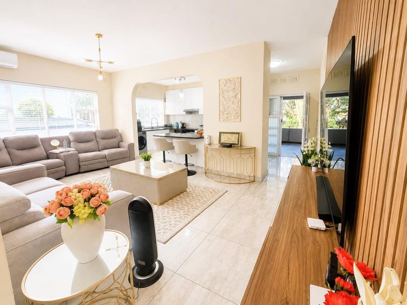 Bright open-plan living area featuring tiled floors, a modern kitchen with island, and a stylish slatted wood feature wall.