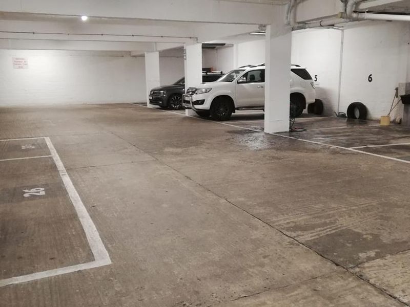 Underground parking garage featuring concrete flooring, numbered parking bays, and exposed ceiling infrastructure.