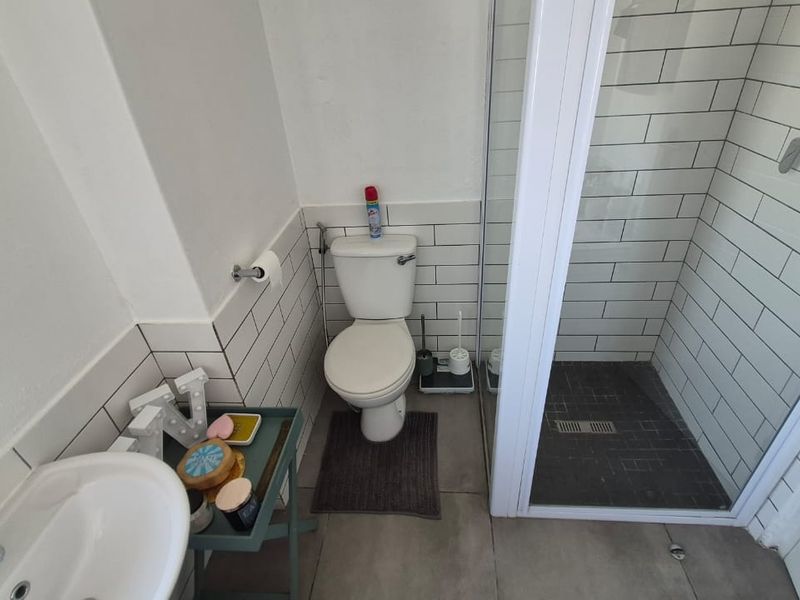 A modern bathroom featuring subway tile wall cladding, a glass-enclosed shower, a pedestal basin, and a standard toilet.