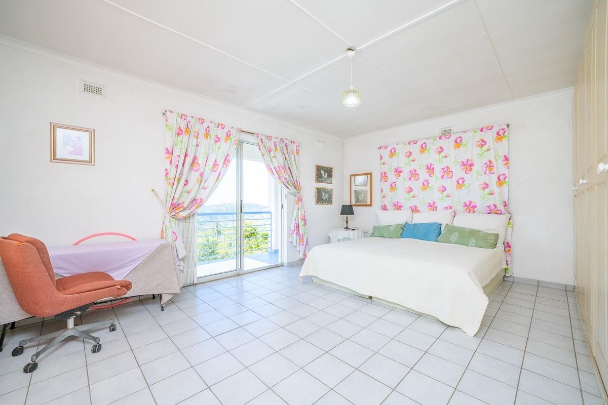 Spacious bedroom featuring tiled flooring, built-in wardrobes, and a sliding glass door providing access to an outdoor balcony area.