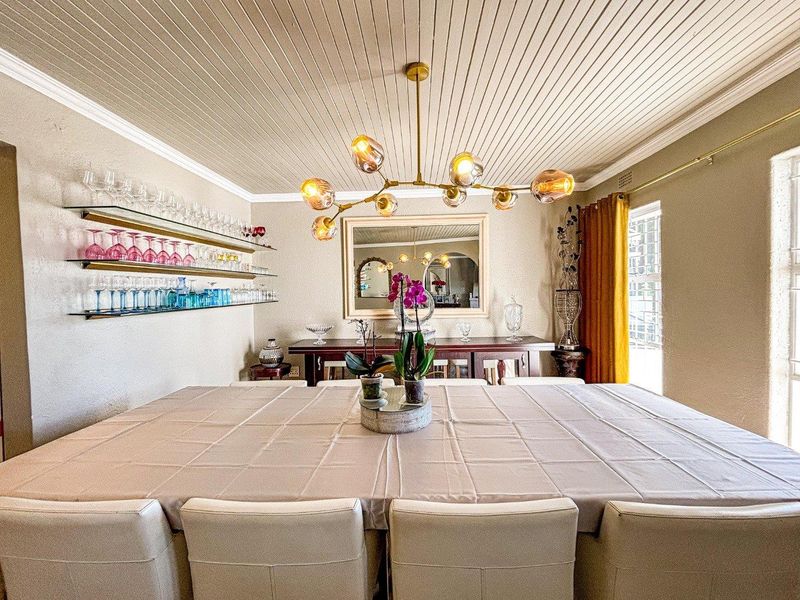 A well-maintained dining room featuring a distinctive tongue and groove ceiling, crown molding, and elegant glass shelving.
