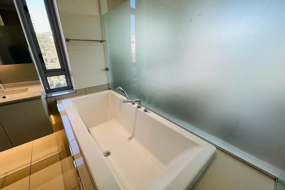 Modern bathroom featuring a built-in bathtub, frosted glass partition, and a vanity unit with integrated sink.