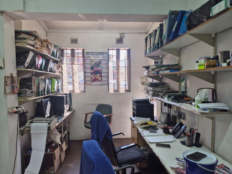 A functional home office space featuring built-in shelving and desk surfaces, equipped with security bars on the windows.