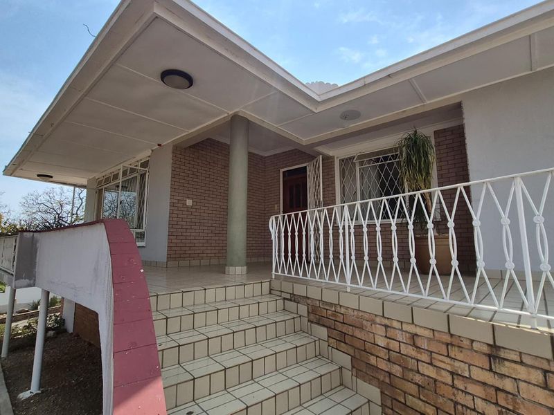 Front entrance area featuring a covered porch, tiled staircase, brick facade, and decorative metal security railings.
