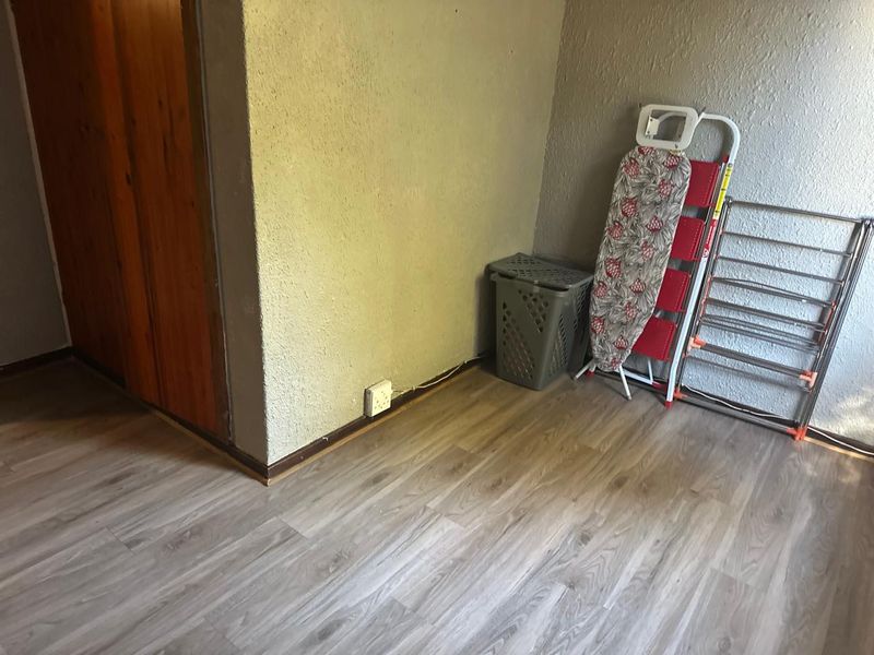 A functional utility or laundry space featuring modern laminate flooring and neutral wall finishes, providing a blank canvas for potential storage or utility upgrades.