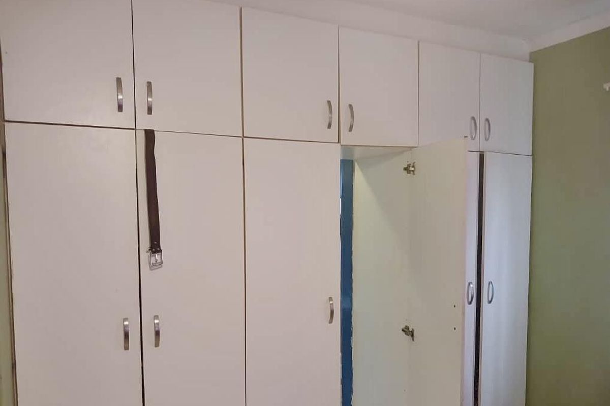 A bedroom featuring built-in white floor-to-ceiling cabinetry with overhead storage compartments.